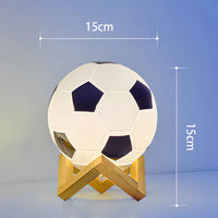 Veilleuse bébé en forme de ballon de football allumée sur une table de chevet